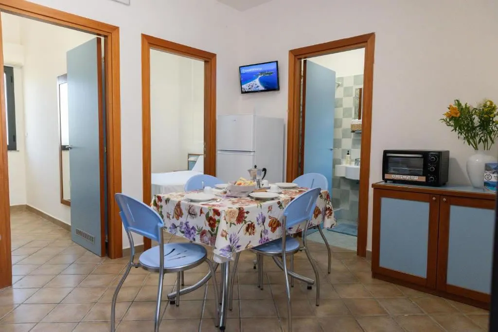 Soggiorno di appartamento con tavolo da pranzo, angolo cottura e accesso a camera e bagno