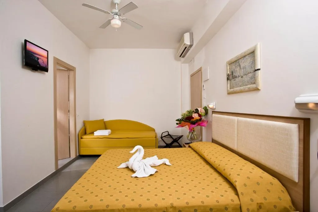Camera con letto matrimoniale giallo, divano, ventilatore a soffitto e aria condizionata