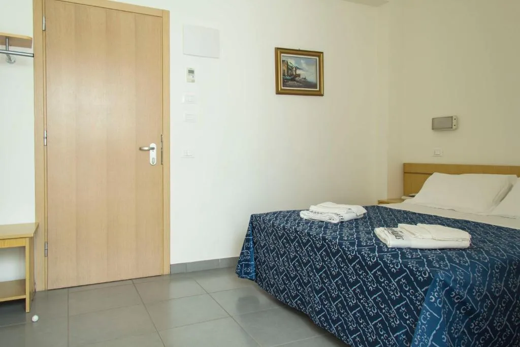 Camera con letto matrimoniale blu, porta in legno, quadro alla parete e pavimento in gres