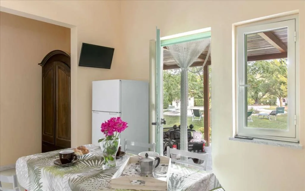Angolo pranzo con tavolo apparecchiato per colazione, frigorifero e vista sul giardino