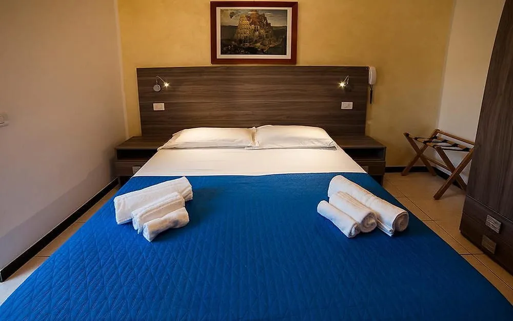Camera matrimoniale con copriletto blu, testiera in legno, comodini e asciugamani arrotolati