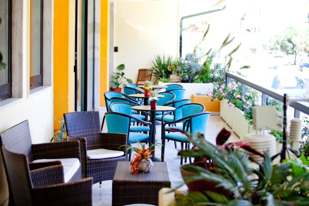 Terrazza esterna con poltrone in vimini, sedie azzurre e piante fiorite