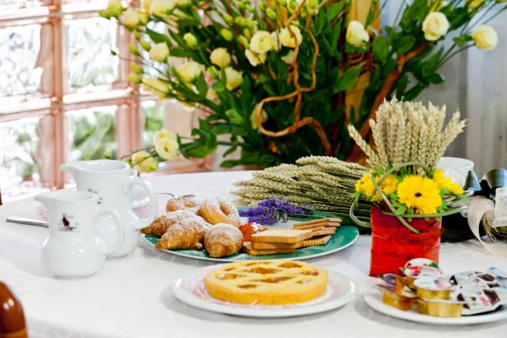 Colazione con cornetti, crostata, biscotti e fiori freschi sul tavolo