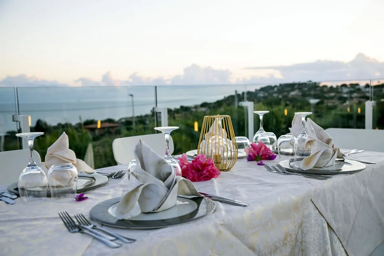 Tavolo elegantemente apparecchiato con vista panoramica sul mare al tramonto