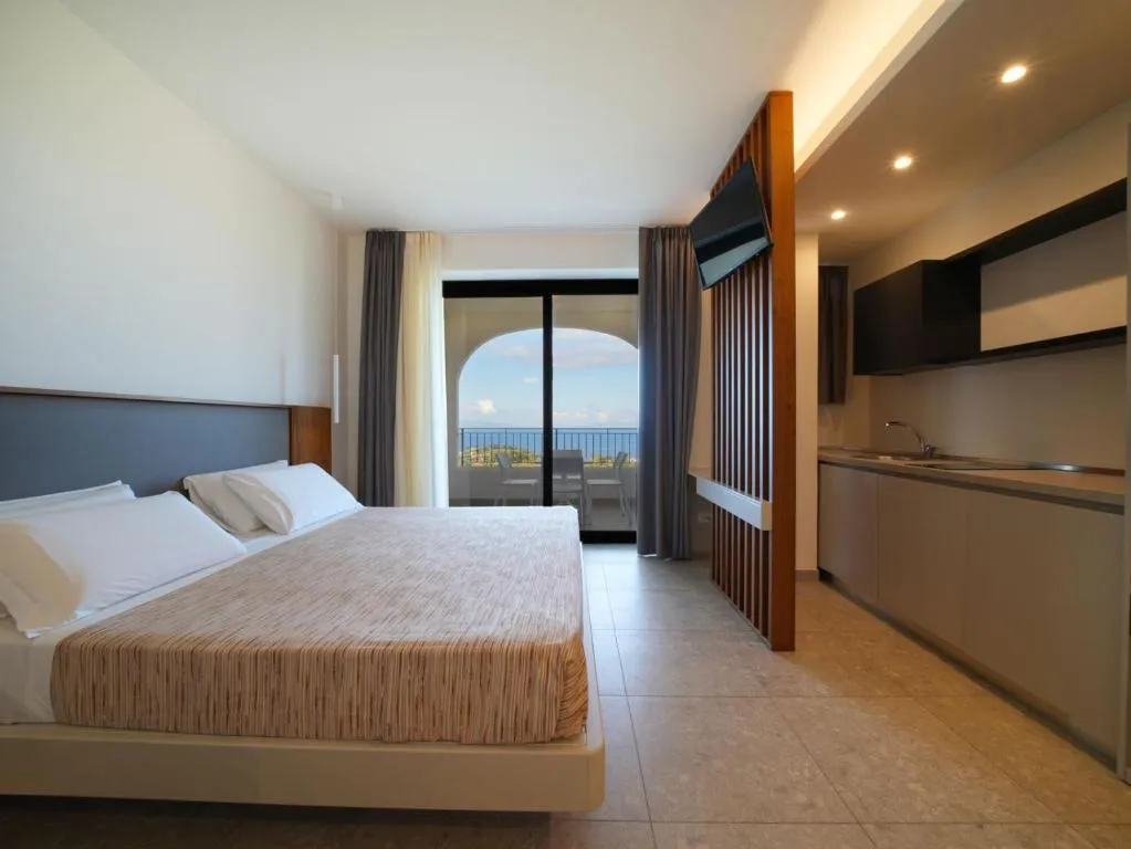 Camera moderna con letto matrimoniale, angolo cucina e balcone vista mare