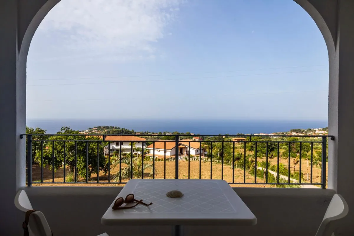 Balcone ad arco con tavolino e vista panoramica sulla campagna e il mare