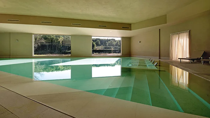Piscina interna con grandi finestre affacciate sul verde