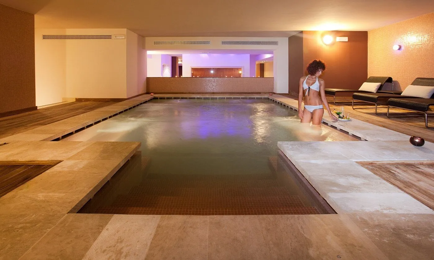 Piscina interna riscaldata della spa con pavimentazione in legno e lettini
