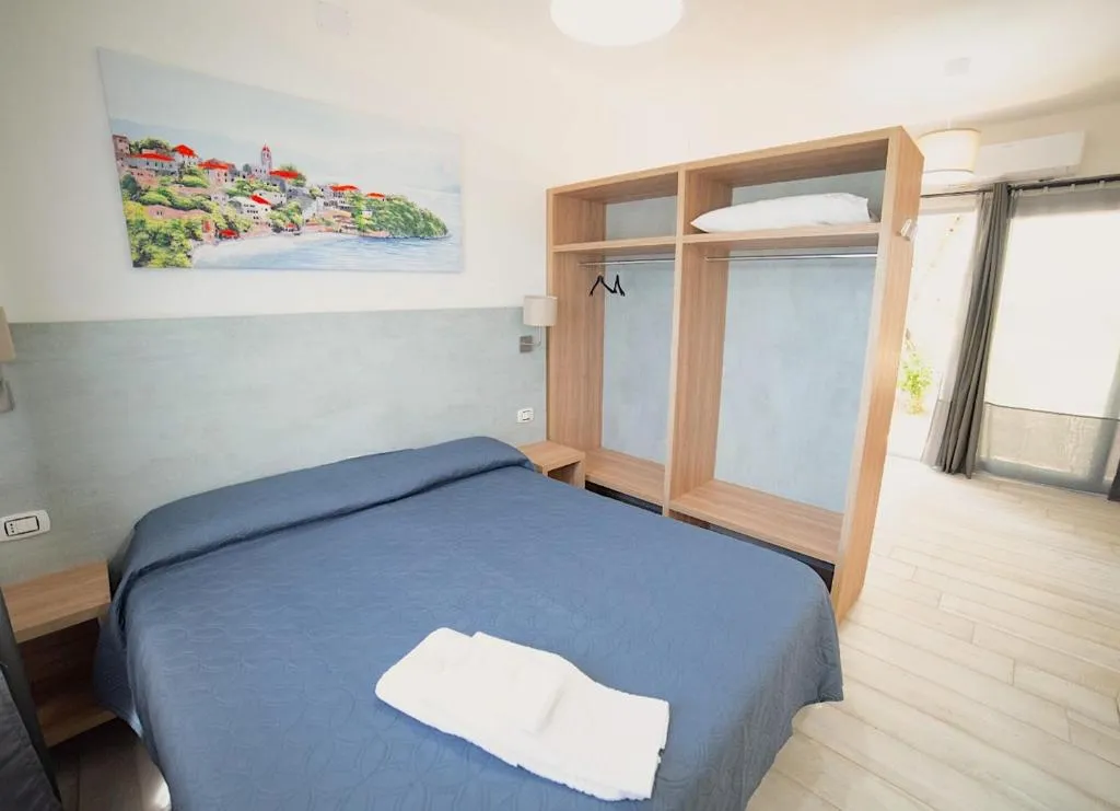 Camera matrimoniale con letto blu, armadio in legno e quadro marino