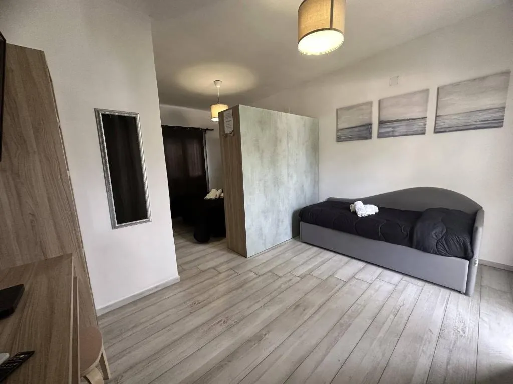Soggiorno luminoso con divano grigio, parquet chiaro e quadri