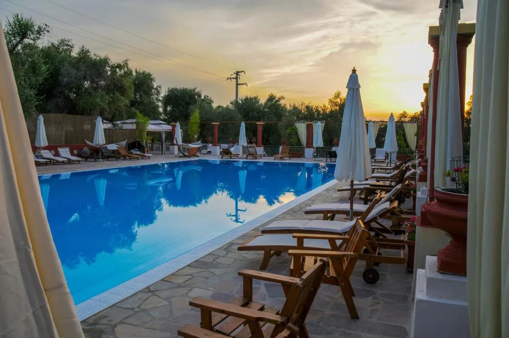 Piscina con lettini in legno e ombrelloni chiusi al tramonto