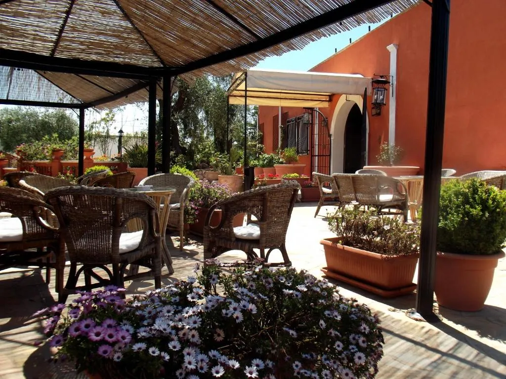 Terrazza esterna coperta con poltrone in vimini e piante fiorite