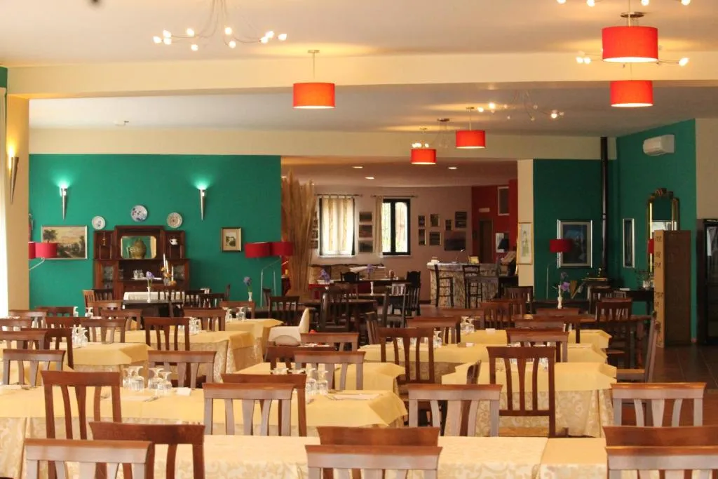 Sala ristorante con tavoli apparecchiati e pareti verdi