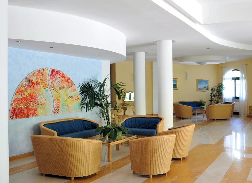 Hall dell'hotel con poltrone in vimini, divani blu e quadro decorativo colorato