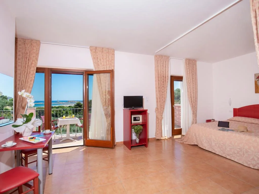 Ampia camera con zona living, scrivania rossa e balcone vista mare