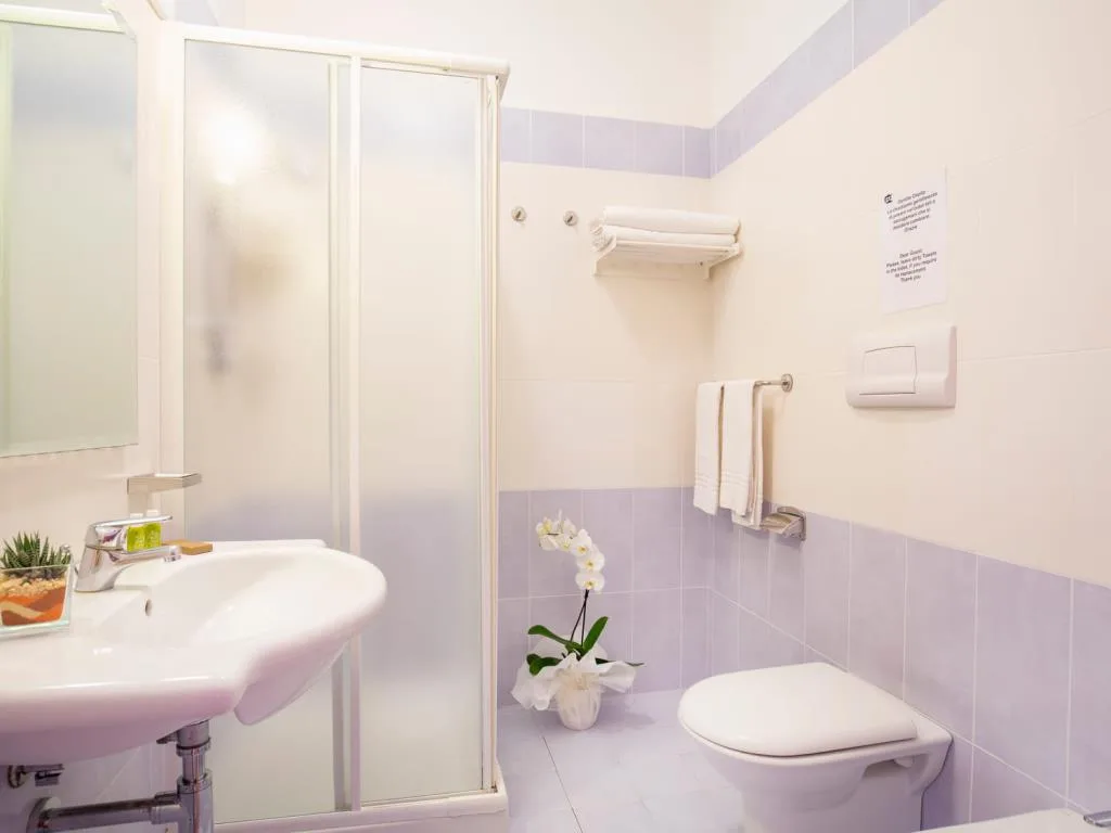 Bagno con piastrelle lilla, doccia, lavabo e sanitari