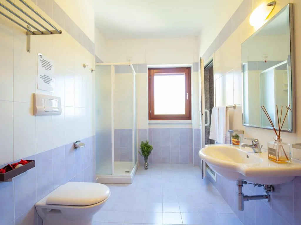 Ampio bagno con piastrelle lilla, doccia, WC e lavabo
