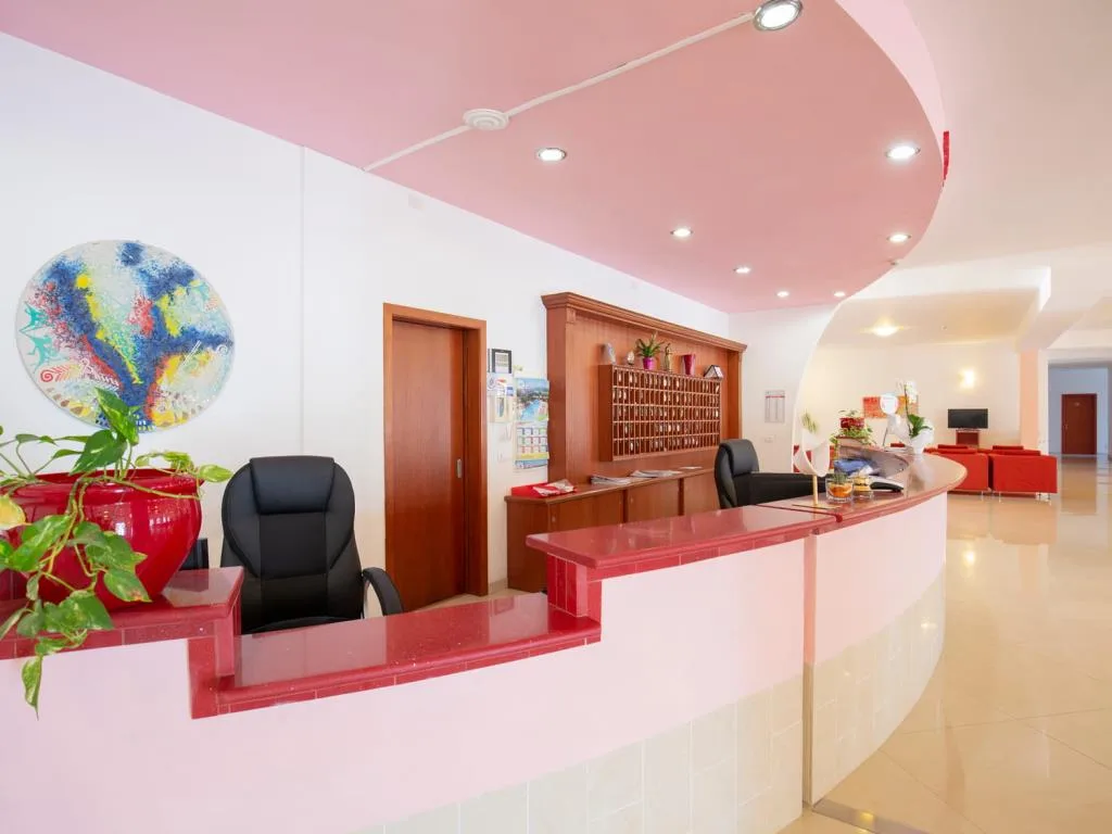 Reception dell'hotel con bancone rosso e soffitto rosa