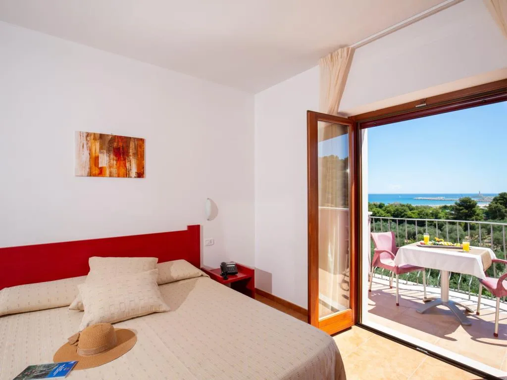 Camera con letto e porta finestra aperta su terrazza con vista mare