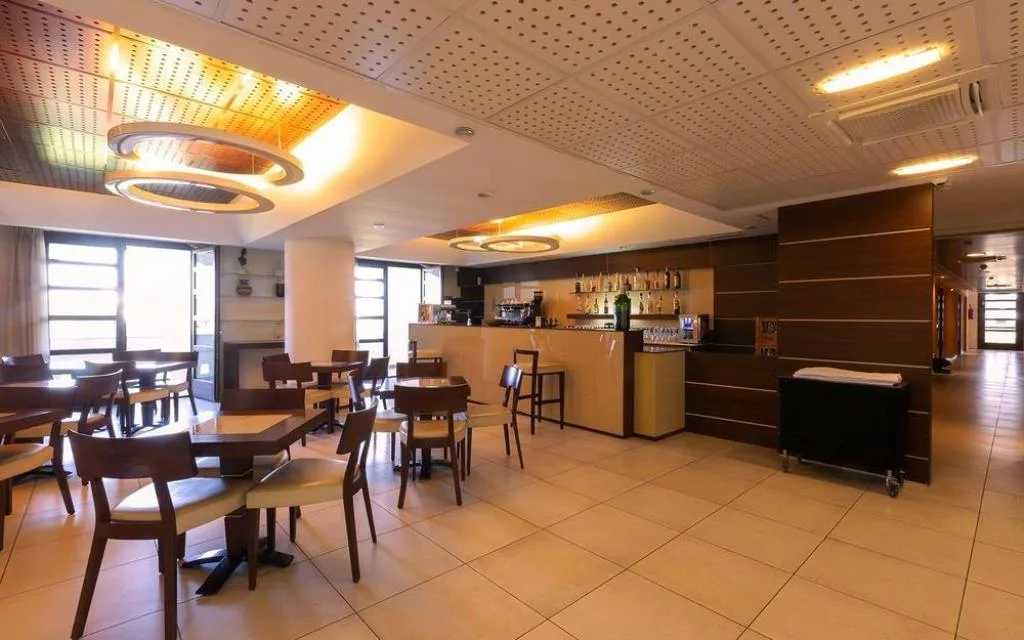 Sala bar con tavoli in legno, sedie e bancone illuminato