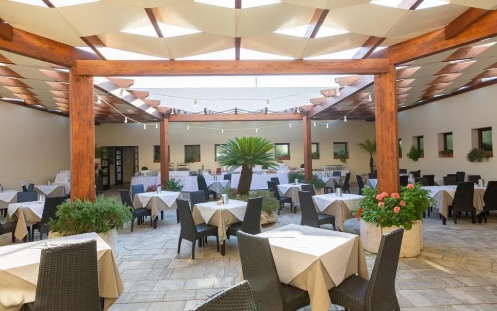 Ristorante interno con pergolato in legno, tavoli apparecchiati e piante