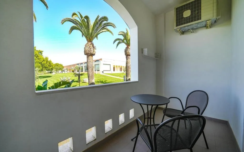 Balcone con tavolino, sedie e vista sul giardino con palme