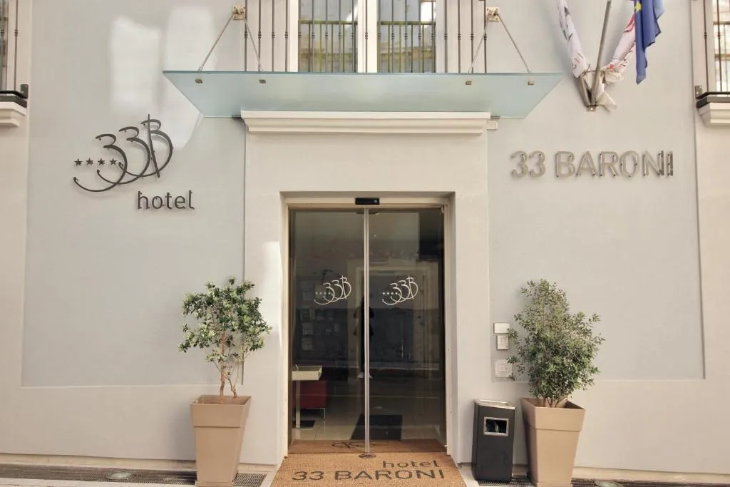 Ingresso dell'Hotel 33 Baroni con porta vetrata, insegna e piante decorative
