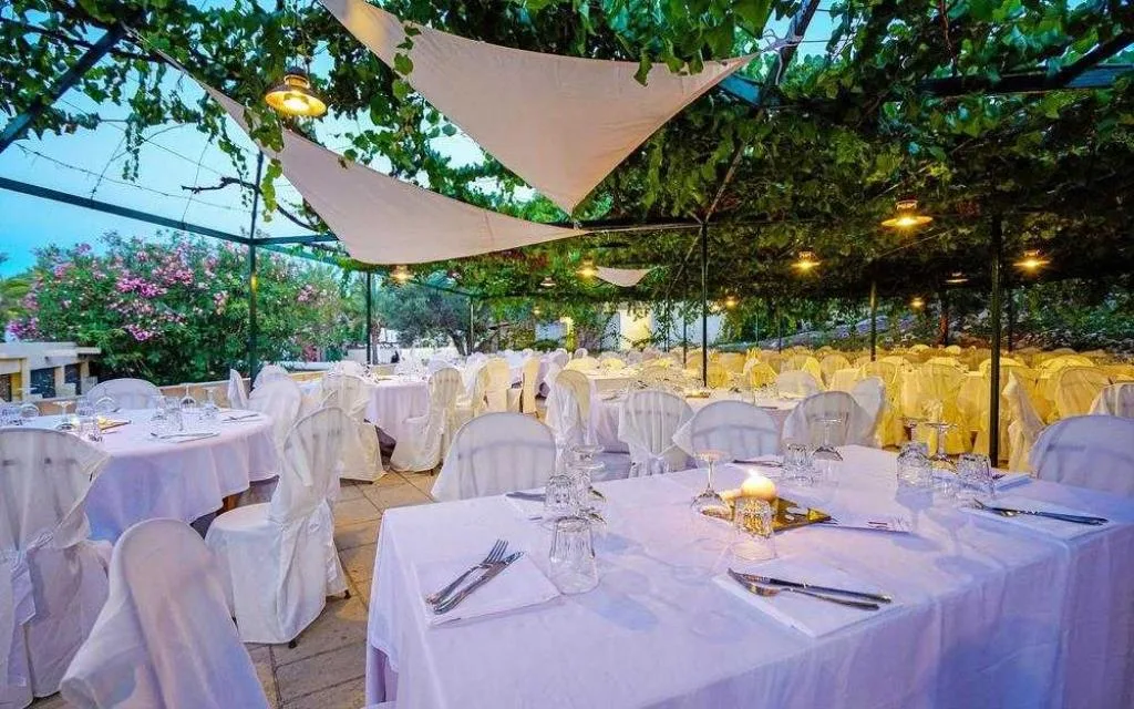 Ristorante all'aperto con tavoli eleganti sotto pergolato e teli ombreggianti