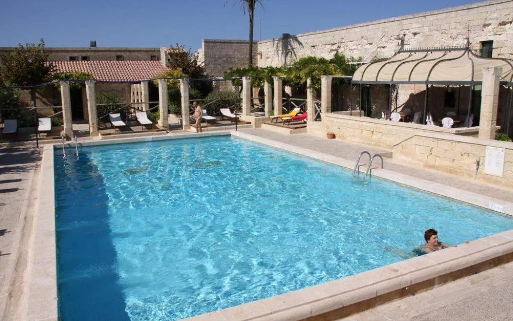 Piscina in cortile storico con colonne in pietra e lettini
