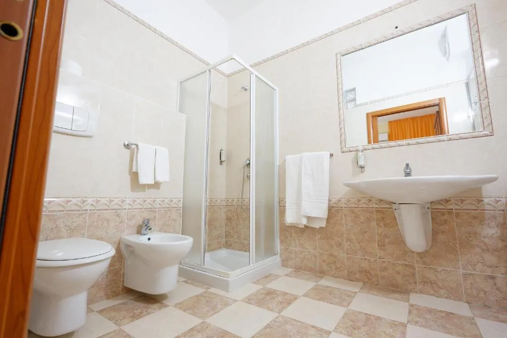 Bagno con doccia, lavabo, bidet, WC e pareti piastrellate beige
