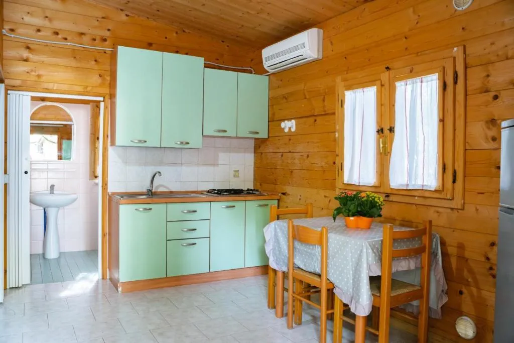 Cucina in legno con mobili verde acqua, tavolo da pranzo e bagno annesso