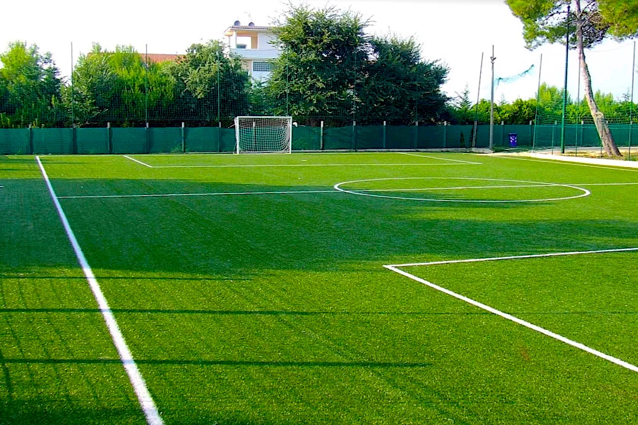 Campo da calcetto in erba sintetica con porta e recinzione verde