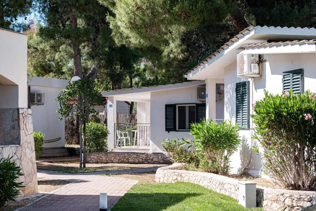 Bungalow bianchi con persiane verdi e giardino curato tra i pini