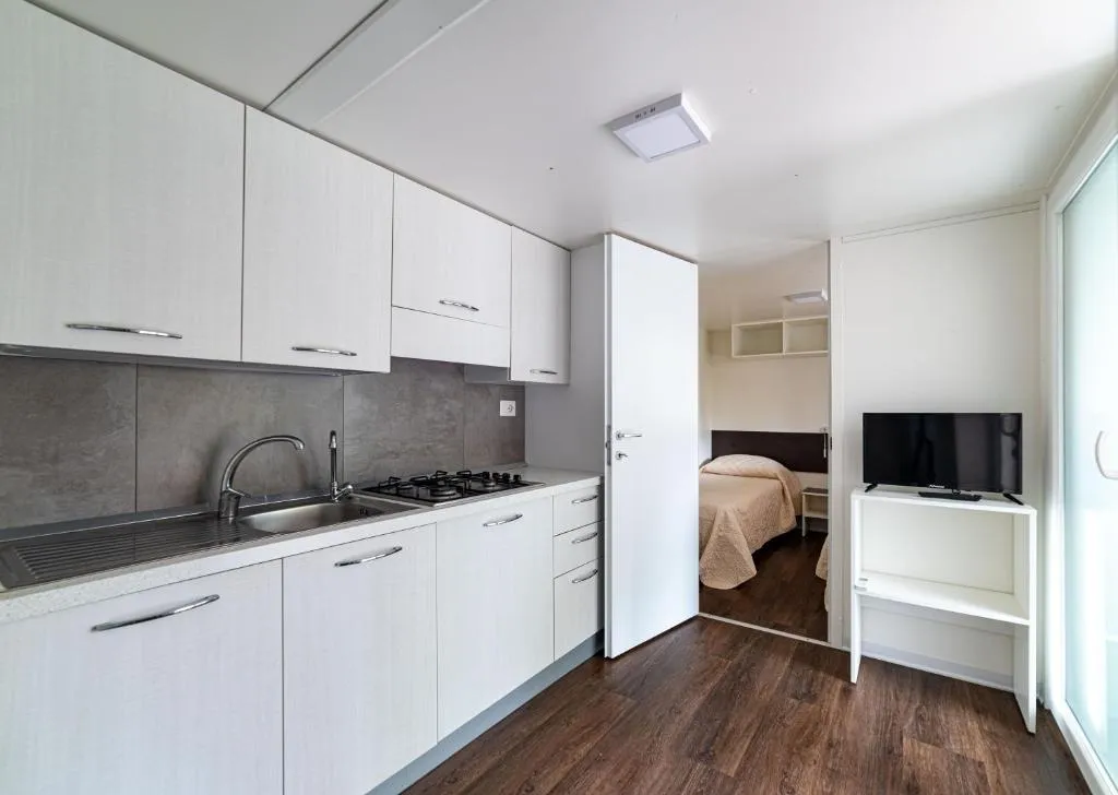 Cucina moderna con mobili bianchi e camera da letto adiacente