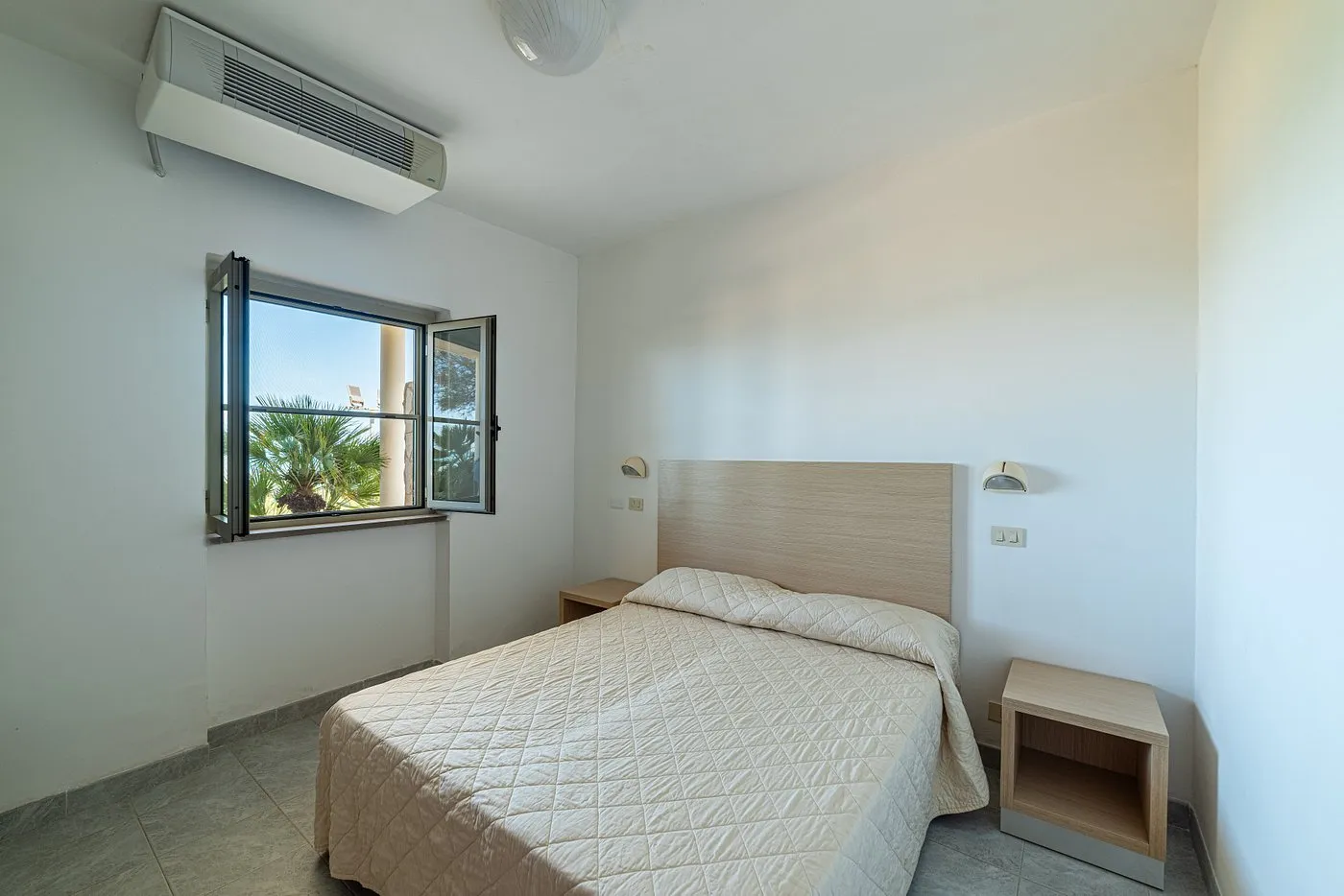 Camera da letto matrimoniale con climatizzatore e finestra affacciata sul verde