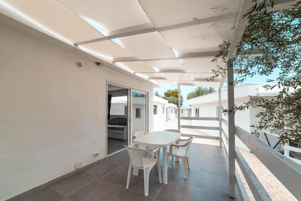 Ampia veranda coperta con tavolo e sedie bianche e pergolato