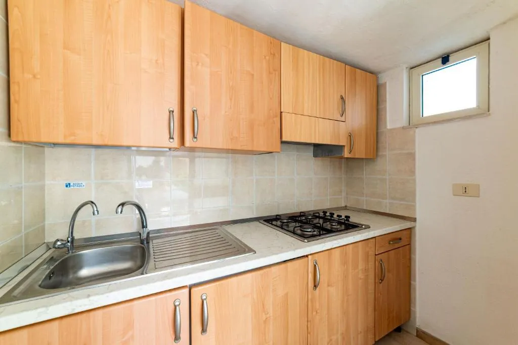 Cucina con mobili in legno chiaro, lavello e piano cottura
