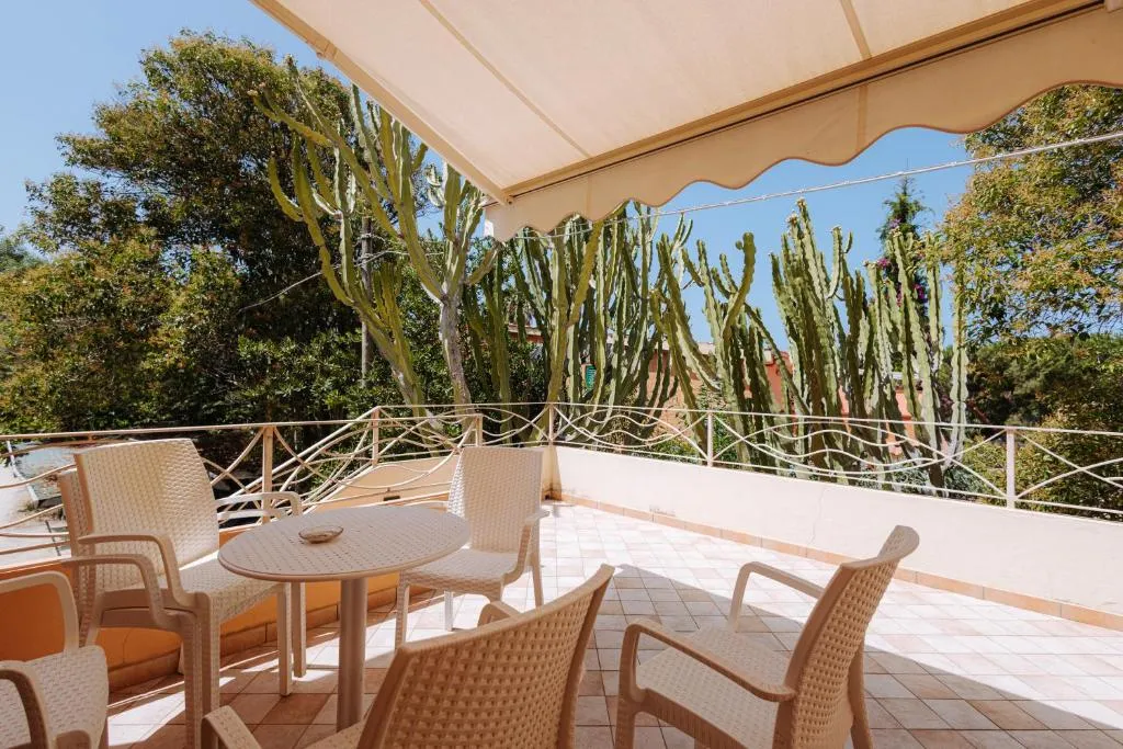 Terrazza privata con tavolo, sedie e tettoia, affacciata su giardino con piante grasse