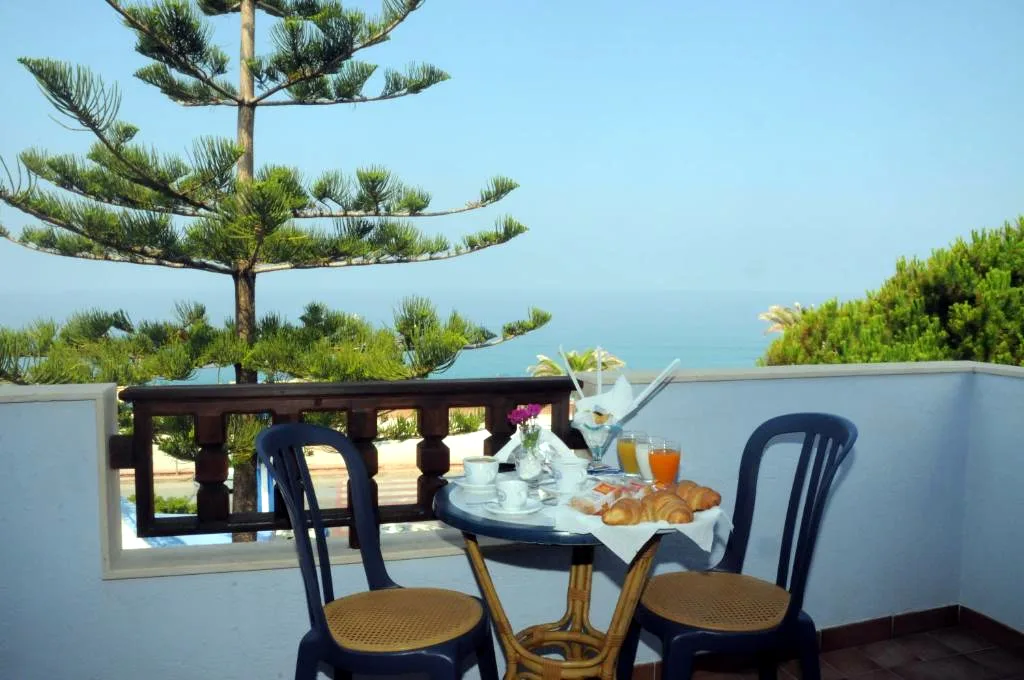 Tavolo apparecchiato per la colazione su terrazza con vista sul mare e pini
