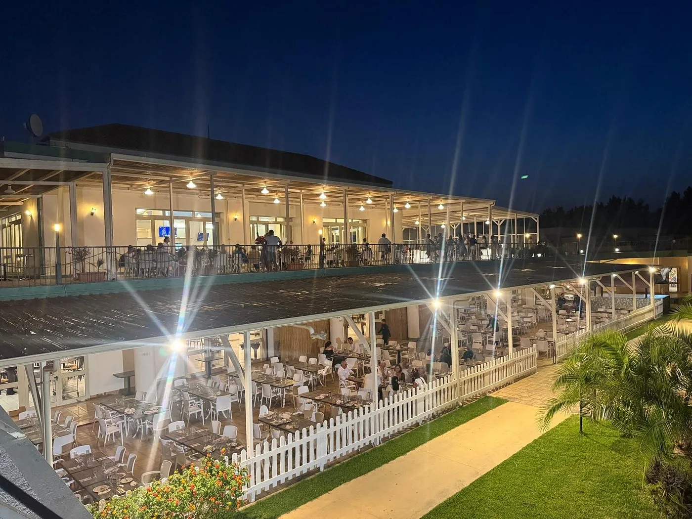Ristorante del resort illuminato di sera su due livelli con terrazza