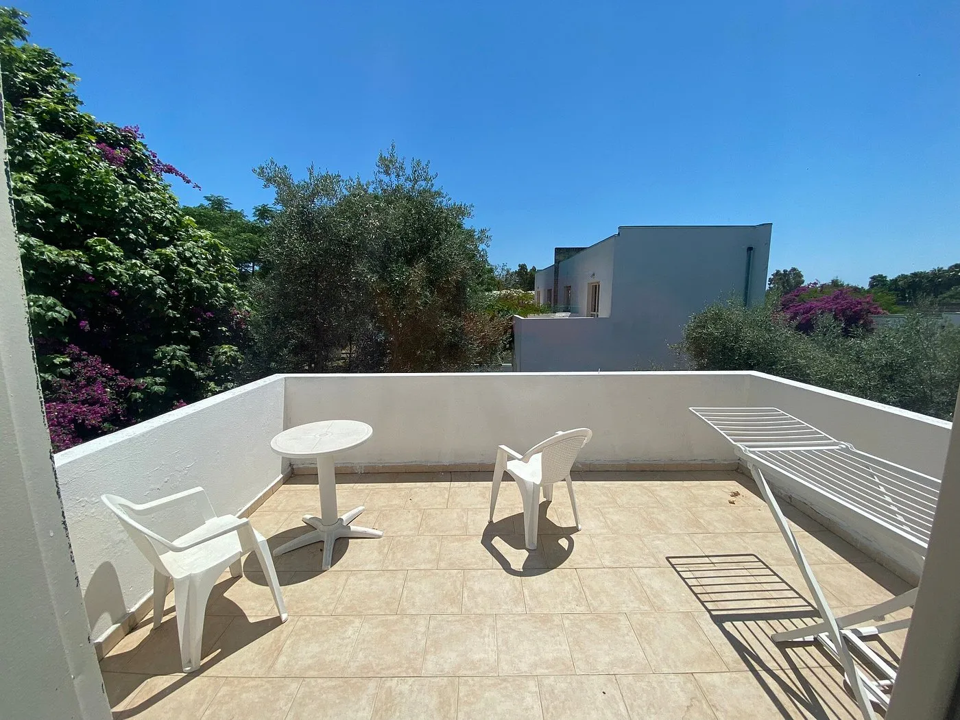 Terrazza privata di una camera con tavolino e sedie bianche