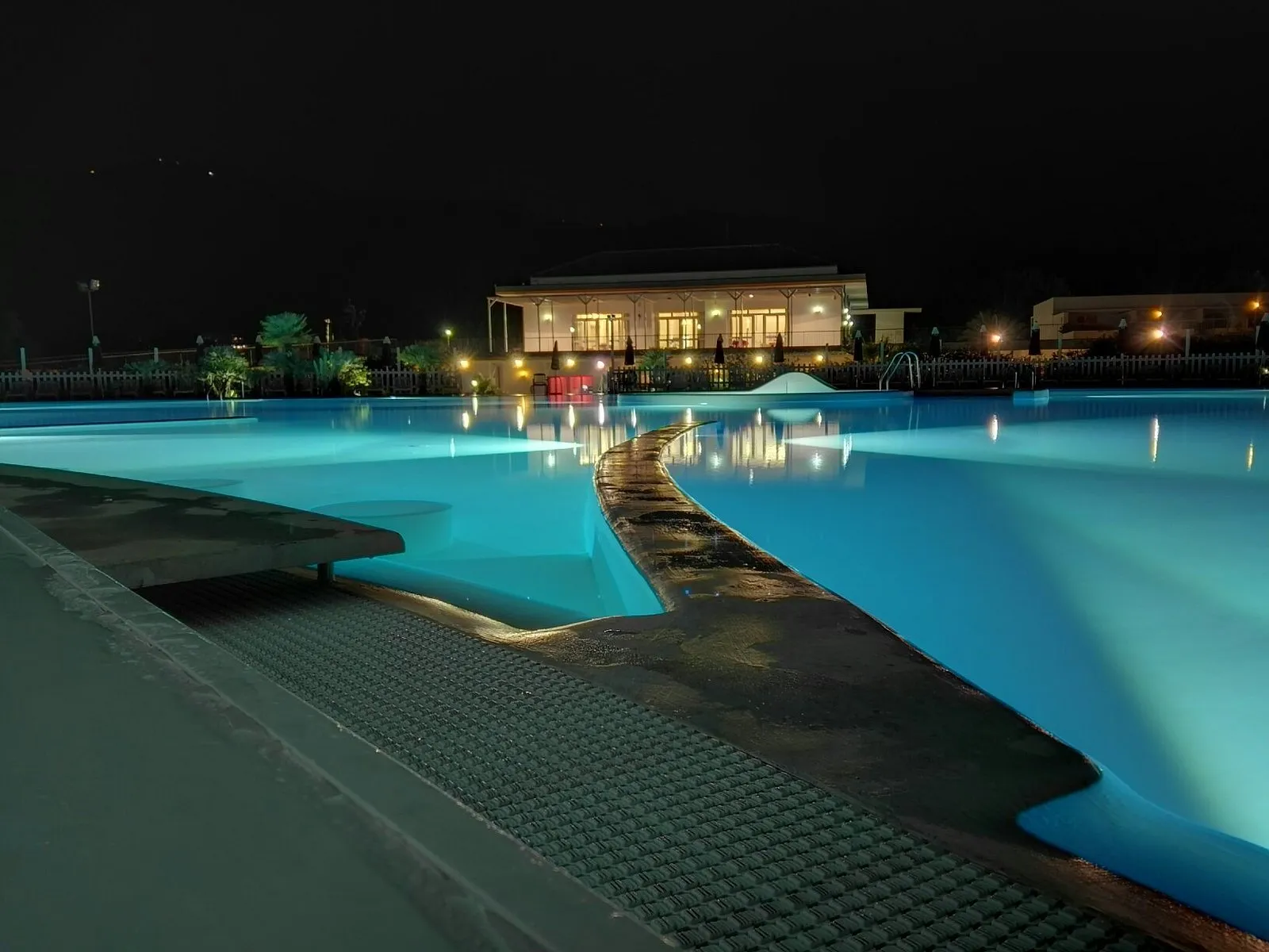 Piscina del resort illuminata di notte con edificio sullo sfondo