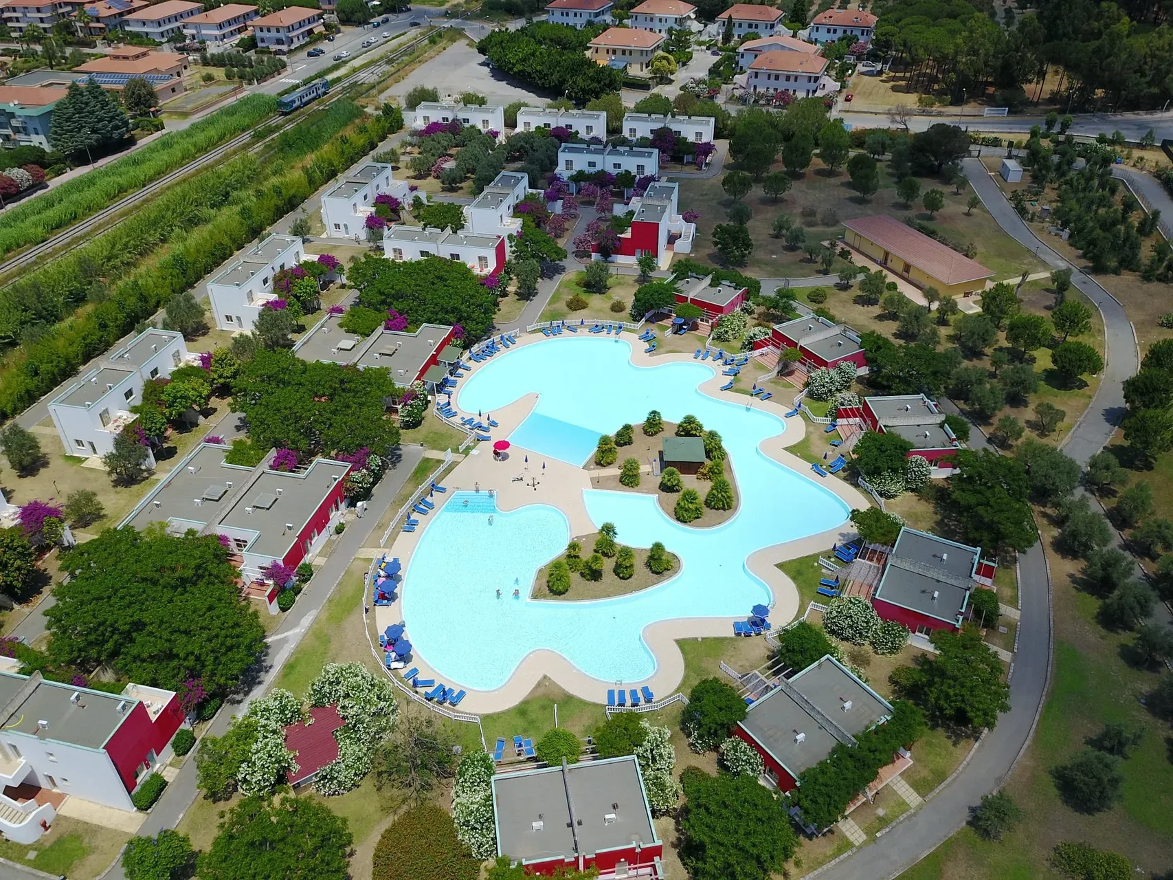 Vista aerea del villaggio con piscina sagomata e bungalow nel verde