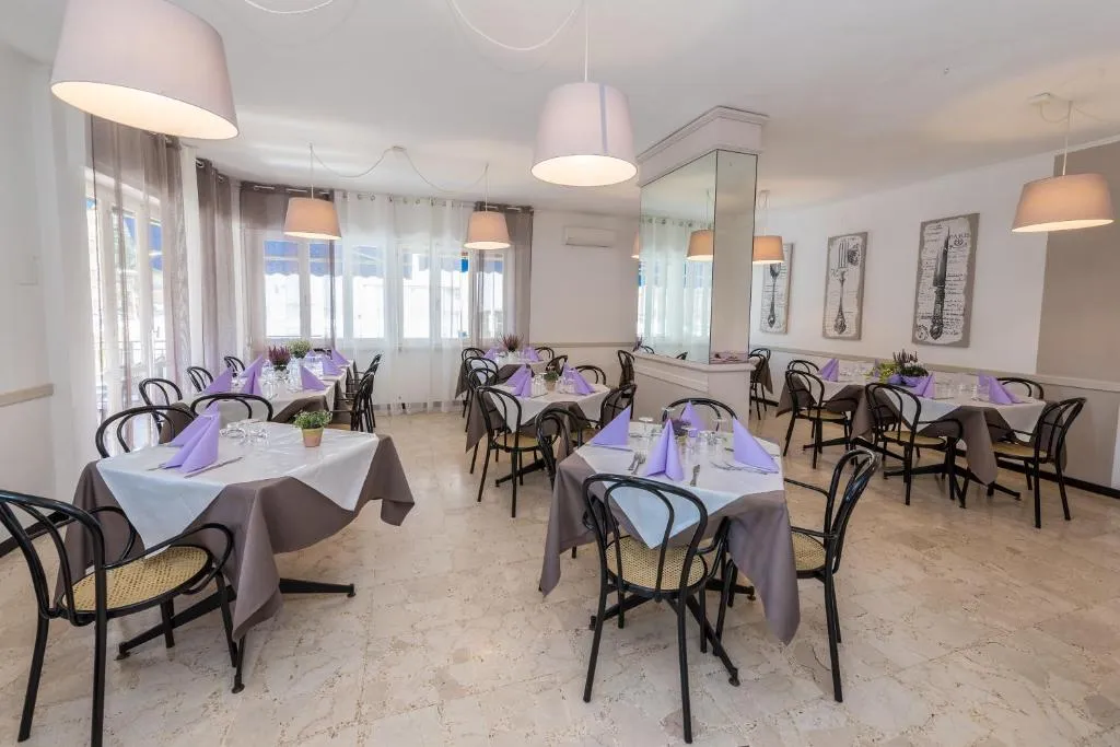 Sala ristorante luminosa con tavoli e tovaglioli lilla