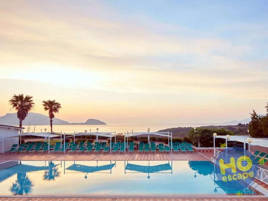 Piscina al tramonto con palme, lettini verdi e cielo rosato sul mare