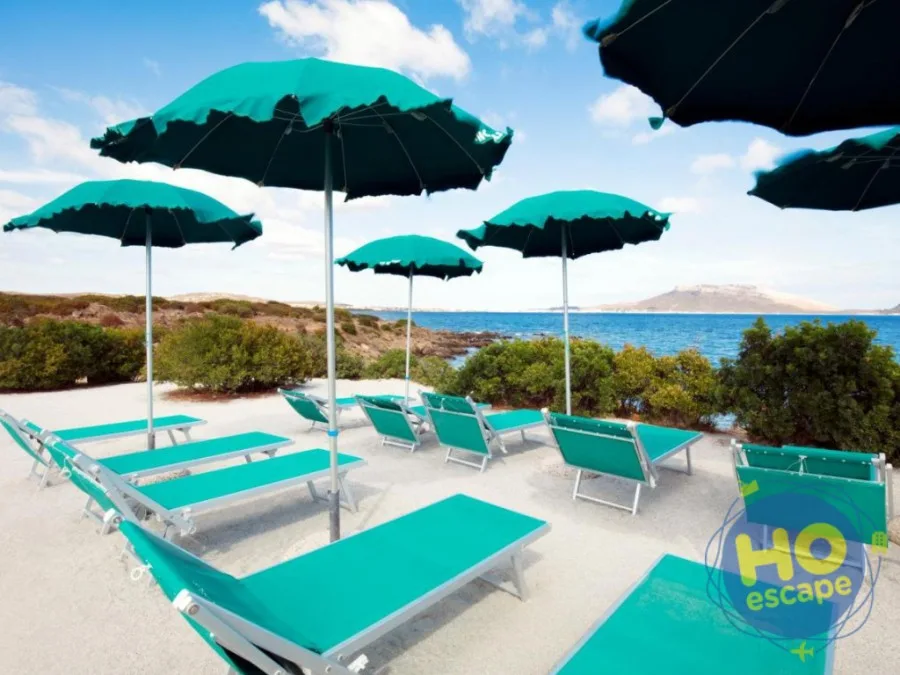 Ombrelloni verdi e lettini su spiaggia di sabbia bianca affacciata sul mare cristallino