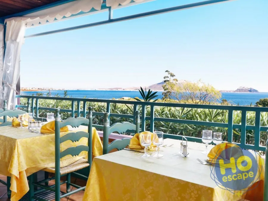 Tavoli apparecchiati con tovaglie gialle su terrazza panoramica con vista sul mare