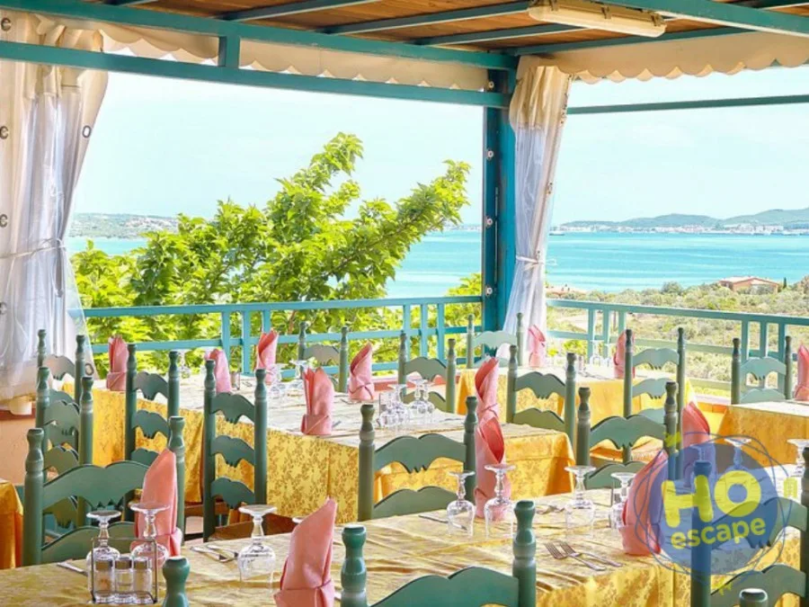 Sala ristorante con terrazza coperta, tavoli apparecchiati e vista panoramica sul mare