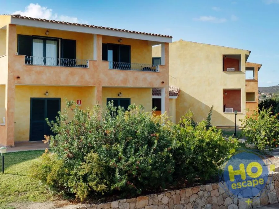 Esterno delle camere dell'hotel in giallo con balconi e giardino curato