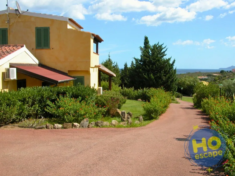 Edificio in stile mediterraneo con giardino e viale, vista sul mare in lontananza
